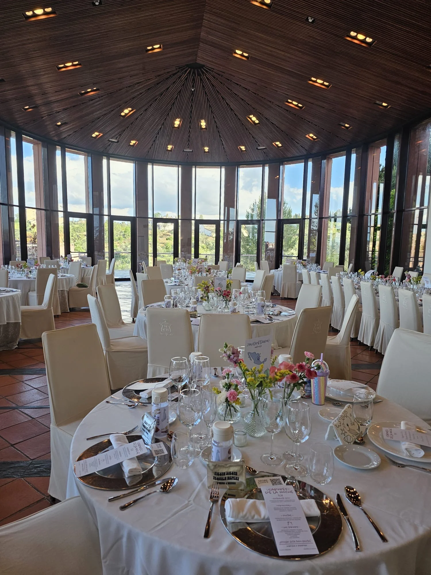 Salón de boda preparado con mesas redondas y decoración floral